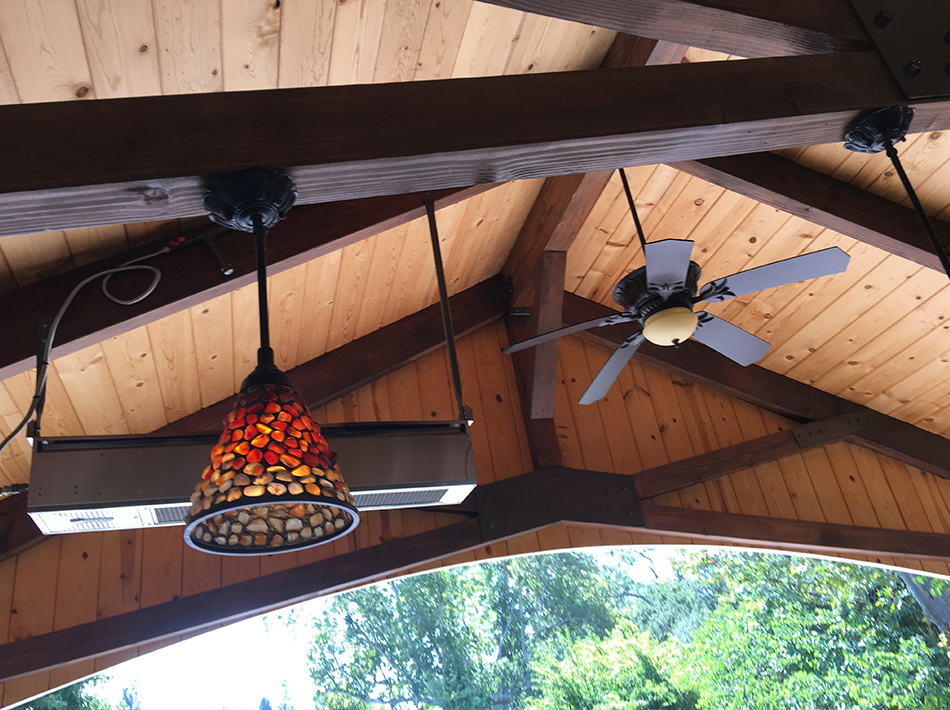 Vaulted timber Ramada ceiling with a fan, decorative pendant light, and integrated outdoor heaters