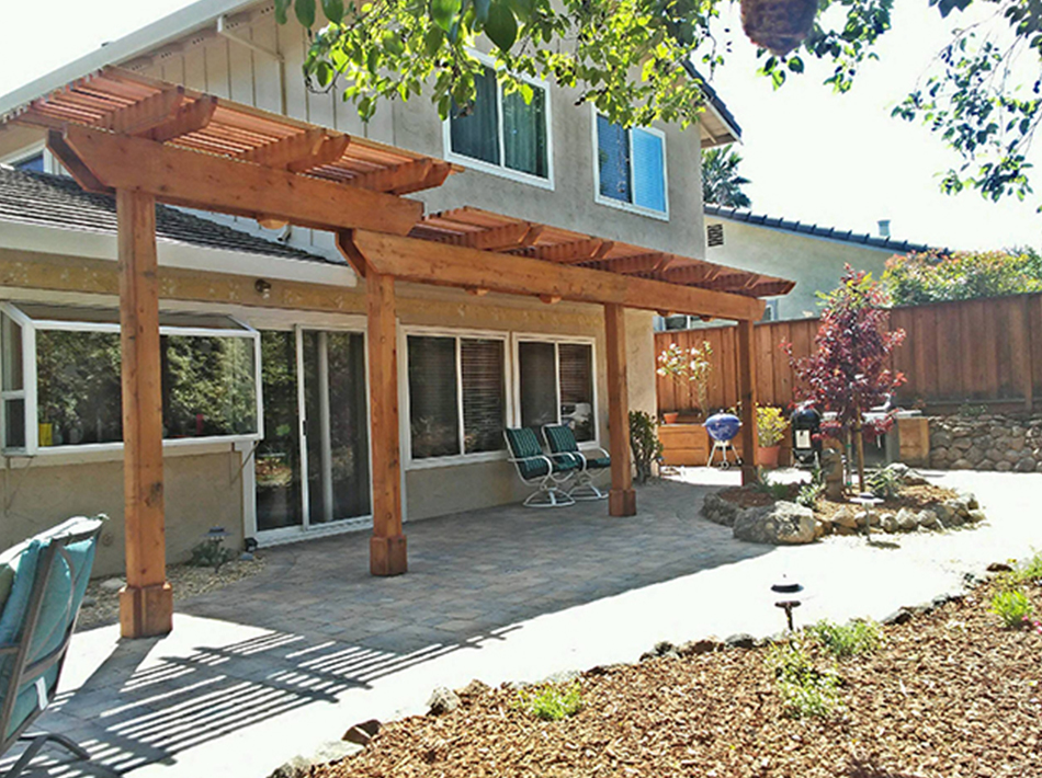 Completed backyard landscape with a custom wood arbor covering a paved patio